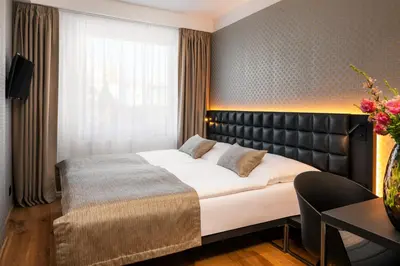 a bedroom with a large bed with a leather headboard at Hotel Aida in Prague
