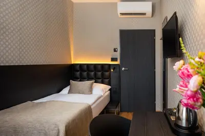 a bedroom with two beds and a table with flowers at Hotel Aida in Prague