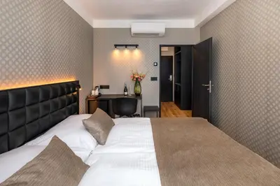 a bedroom with a large white bed with a black headboard at Hotel Aida in Prague