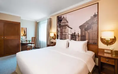 a hotel room with a large white bed with a painting on the wall at Lindner Hotel Prague Castle, part of JdV by Hyatt in Prague