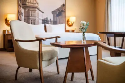 a hotel room with a table and chairs and a bed at Lindner Hotel Prague Castle, part of JdV by Hyatt in Prague