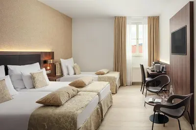 a hotel room with two beds and a desk at Michelangelo Grand Hotel in Prague
