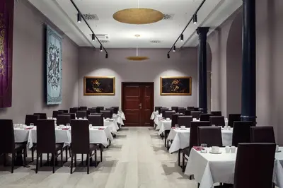 a dining room with white tables and black chairs at Michelangelo Grand Hotel in Prague