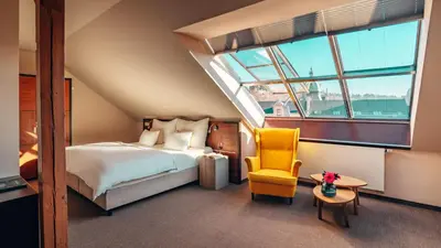 a bedroom with a bed and a chair and a window at Boutique Hotel Klarov in Prague