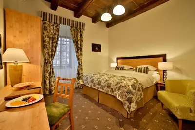a bedroom with a bed and a chair and a table at Hotel Questenberg in Prague