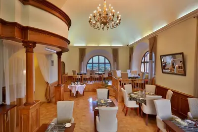a restaurant with tables and chairs and a chandelier at Hotel Questenberg in Prague