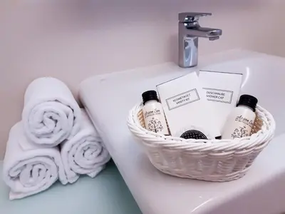 a basket of toiletries sitting on a sink with towels at LH Vintage Design Hotel Sax in Prague