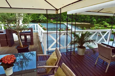 a deck with a table and chairs and a view of a river at Romantic Hotel Mlýn Karlstejn in Karlštejn