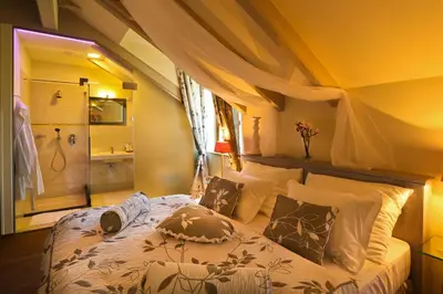 a bedroom with a bed and a bathroom with a shower at Romantic Hotel Mlýn Karlstejn in Karlštejn