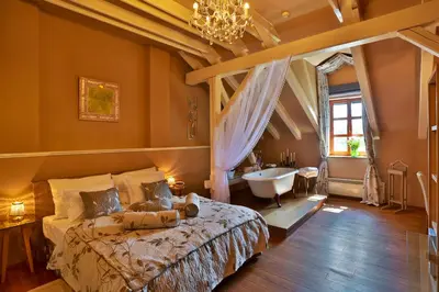 a bedroom with a bed and a tub and a sink at Romantic Hotel Mlýn Karlstejn in Karlštejn