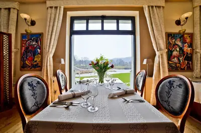 a dining room with a table and a large window at Romantic Hotel Mlýn Karlstejn in Karlštejn