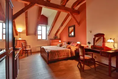 a bedroom with a bed and a desk at Romantic Hotel Mlýn Karlstejn in Karlštejn