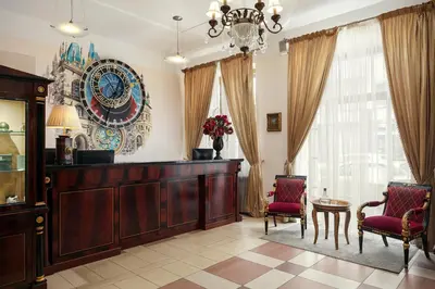 a living room with two chairs and a large clock on the wall at EA Embassy Prague Hotel in Prague