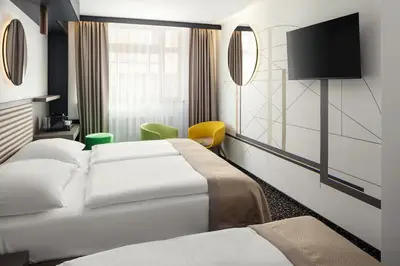 a hotel room with three beds and a tv at EA Embassy Prague Hotel in Prague