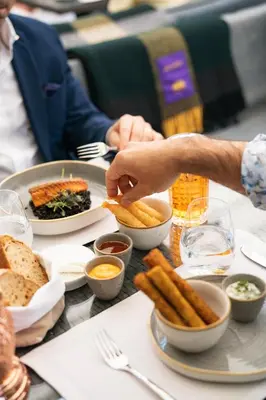 a person eating food on a table with french fries at Mandarin Oriental, Prague in Prague