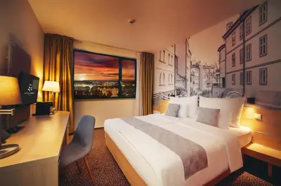 a hotel room with a bed and a desk and a window at Iris Hotel Eden - Czech Leading Hotels in Prague