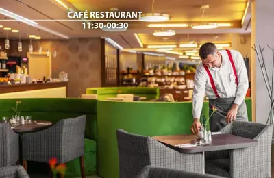 a man standing at a table in a restaurant at Iris Hotel Eden - Czech Leading Hotels in Prague