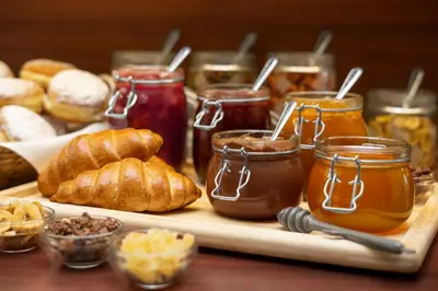 a table with jars of honey and croissants and bread at Iris Hotel Eden - Czech Leading Hotels in Prague