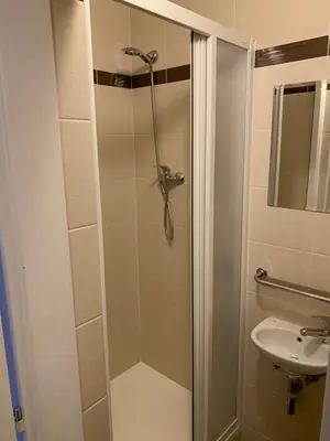 a shower with a glass door next to a sink at City-Inn in Prague