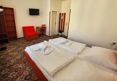 two beds in a hotel room with a red chair at City-Inn in Prague