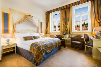 a hotel room with a bed and a desk and chairs at Luxury Family Hotel Royal Palace in Prague
