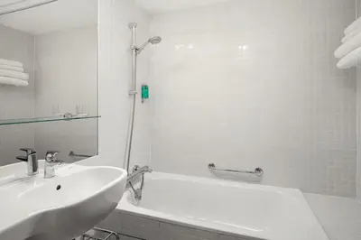 a white bathroom with a tub and a sink at Metropol Design Hotel Old Town in Prague