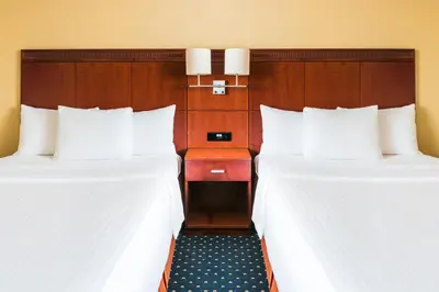 two beds in a hotel room with white sheets at Courtyard by Marriott Prague City in Prague