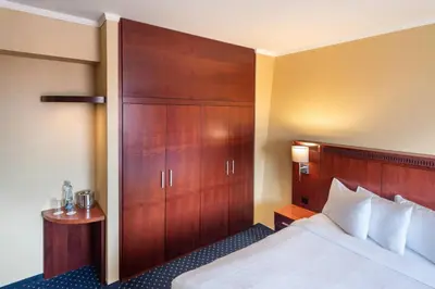 a hotel room with a bed and a wooden cabinet at Courtyard by Marriott Prague City in Prague