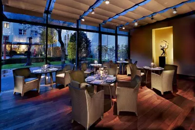 a restaurant with tables and chairs and large windows at The Grand Mark Prague - The Leading Hotels of the World in Prague