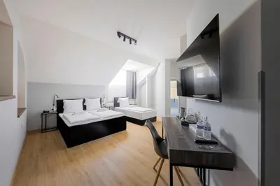 a room with a bed and a desk and a sink at Koruna Hotel in Prague
