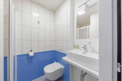 a white bathroom with a toilet and a sink at Koruna Hotel in Prague