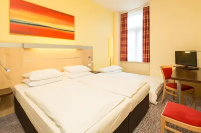 a hotel room with two beds and a desk and a television at Exe City Park Hotel in Prague
