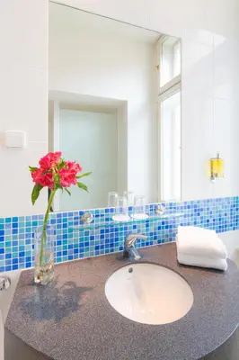 a bathroom with a sink and a vase with a flower at Exe City Park Hotel in Prague