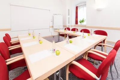 a conference room with long tables and red chairs at Exe City Park Hotel in Prague
