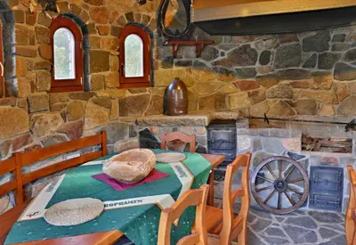 a dining room with a table and a stone wall at Zámeček Kaliště in Poddubí