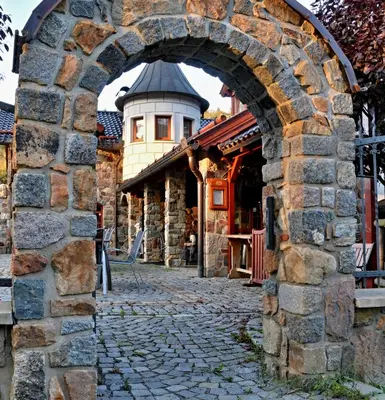 an archway in a stone wall with a building at Zámeček Kaliště in Poddubí