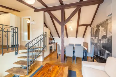 a living room with a staircase and a table and chairs at Janackovo - Riverside Residence in Prague