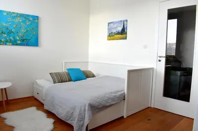 a white bedroom with a bed and a window at Airstay Prague apartment: Grebovka in Prague