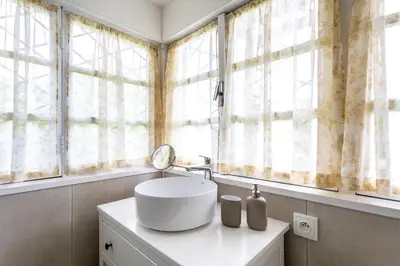 a bathroom with a white sink and windows at Private summer house with swimming pool, beach bar and pit for football and volleyball in Hvězdonice
