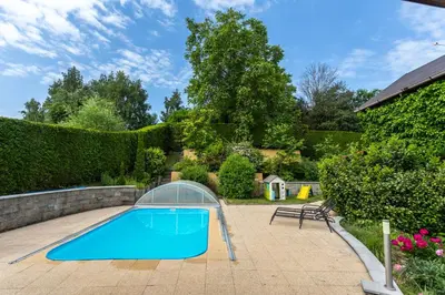 a blue swimming pool with a greenhouse around it at Private summer house with swimming pool, beach bar and pit for football and volleyball in Hvězdonice
