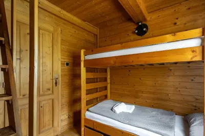 a bedroom with two bunk beds in a log cabin at Private summer house with swimming pool, beach bar and pit for football and volleyball in Hvězdonice
