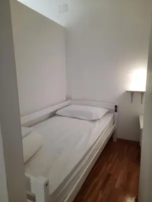 a small white bed in a small room at NEW GENERATION HOSTEL Prague center in Prague