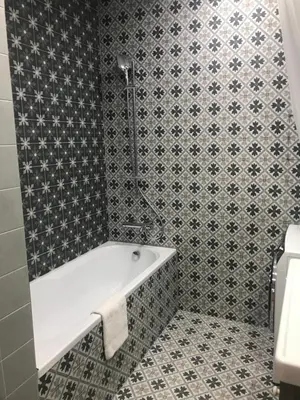 a bathroom with a white bath tub and a tile wall at ATTIC APARTMENT on WATERFRONT / VIEW / NETFLIX in Prague