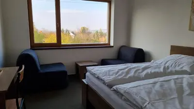 a bedroom with a bed and two chairs and a window at Pension Vinařství Klučov in Klučov