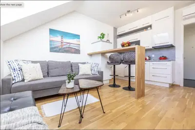 a living room with a gray couch and a kitchen at Minimalist's Dream - sunny cozy studio in New Town in Prague