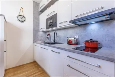 a kitchen with white cabinets and a red pot on the stove at Minimalist's Dream - sunny cozy studio in New Town in Prague