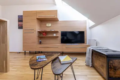 a living room with a tv and a table at Minimalist's Dream - sunny cozy studio in New Town in Prague