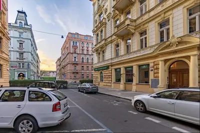 two cars parked on a city street with buildings at Minimalist's Dream - sunny cozy studio in New Town in Prague