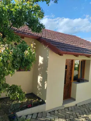 a small white house with a wooden door at Malé útulné studio s koupelnou a kuchyňkou in Svinařov