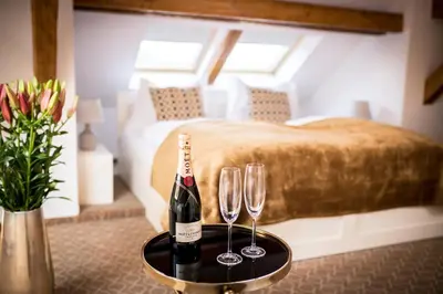a room with a bed and two wine glasses on a table at Hotel Golfi in Poděbrady